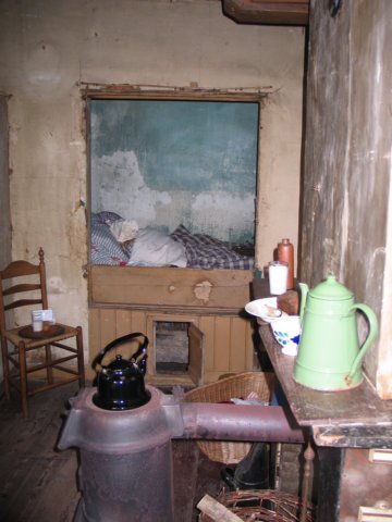Huiskamer met bedstede en potkachel in het wevershuis
